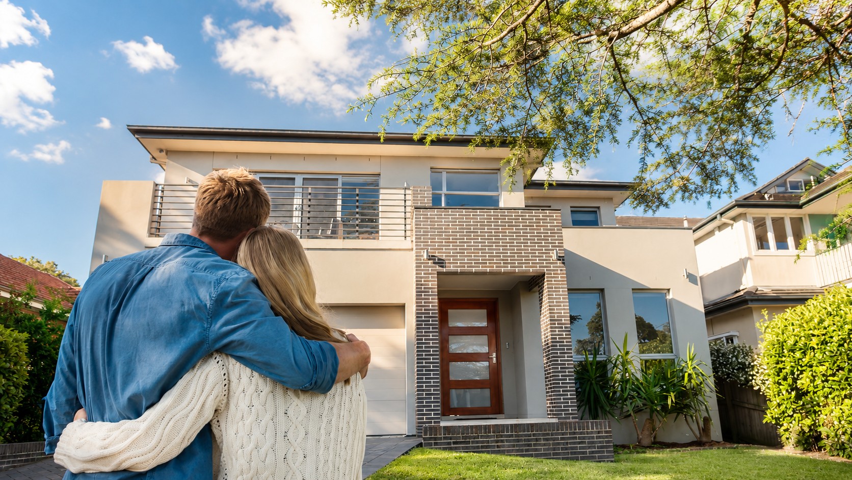 Couple standing in front of a bright modern home